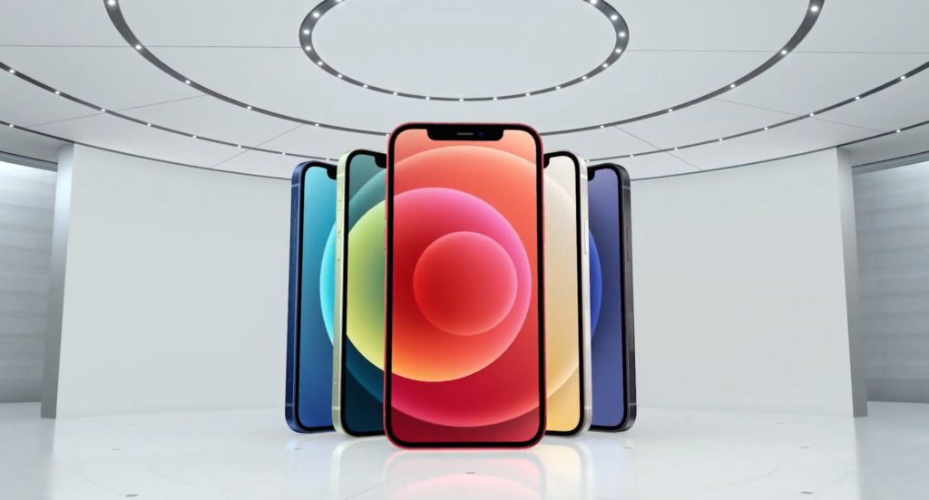 Cinq iPhones de couleurs différentes debout les uns derrière les autres en forme de V sur fond blanc