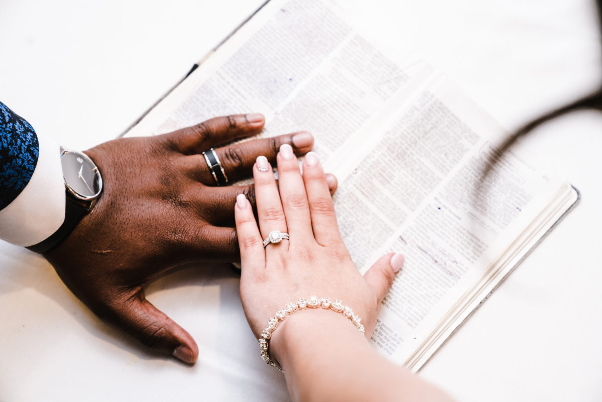 couple plaçant la main sur la bible avec des alliances