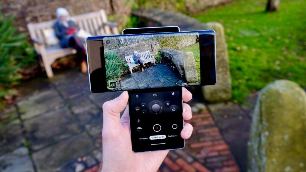 Un smartphone LG Wing tenu en main, appareil photo ouvert sur un écran et boutons pour cliquer sur l'image sur l'autre