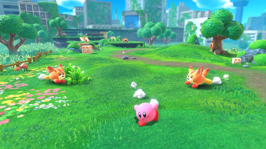 Kirby courant à travers l'herbe, devant les renards ennemis