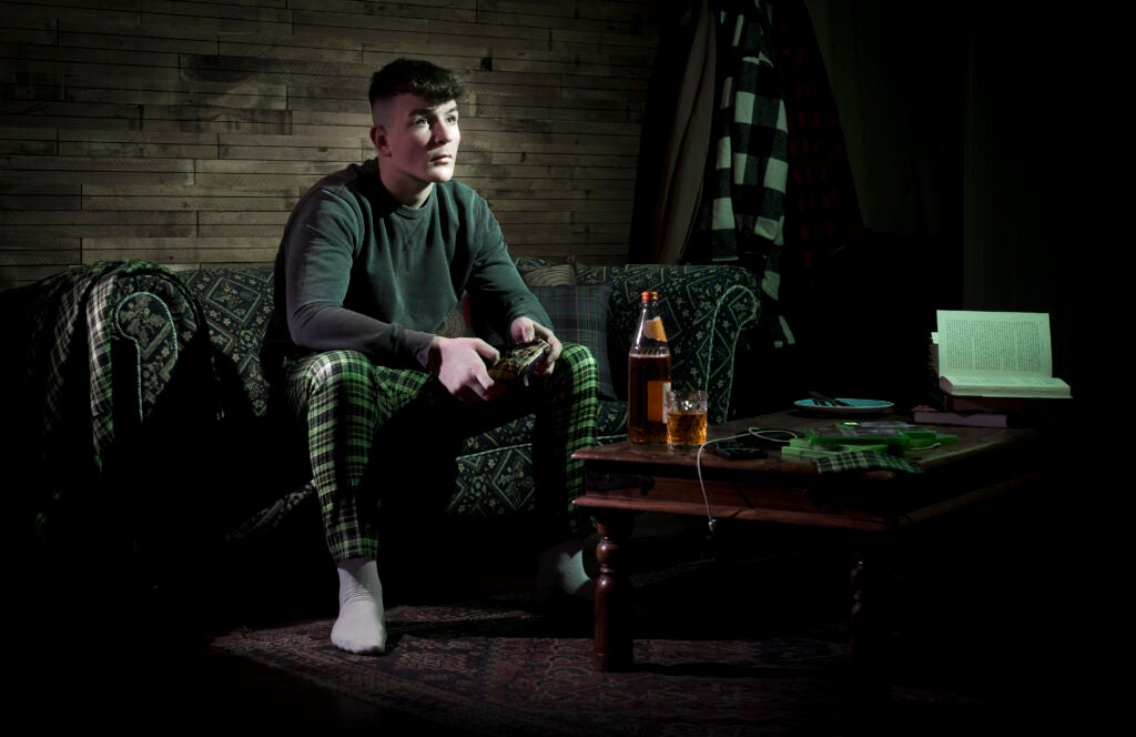 Un homme assis avec une manette Xbox dans un monde de tartan grâce à l'Écosse