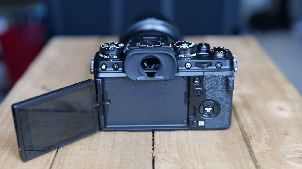 Vue arrière d'un appareil photo Fujifilm XT4 noir debout sur une table en bois avec son écran ouvert