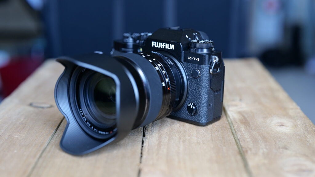 Vue à angle droit d'un appareil photo Fujifilm XT4 noir posé sur une table en bois, vue latérale avant