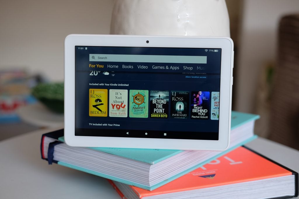 Un Amazon Kindle blanc debout sur des livres affichant l'écran d'accueil du magasin