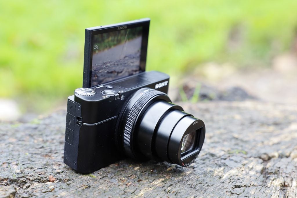 Vue en angle gauche d'un appareil photo Sony RX100 VII noir posé sur le sol avec son écran arrière retourné vers l'avant