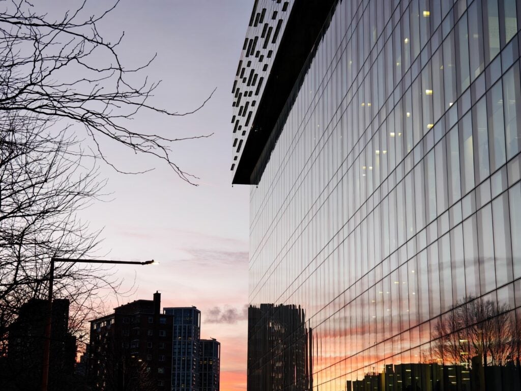 Réflexion urbaine au coucher du soleil sur la façade en verre d'un bâtiment moderne.