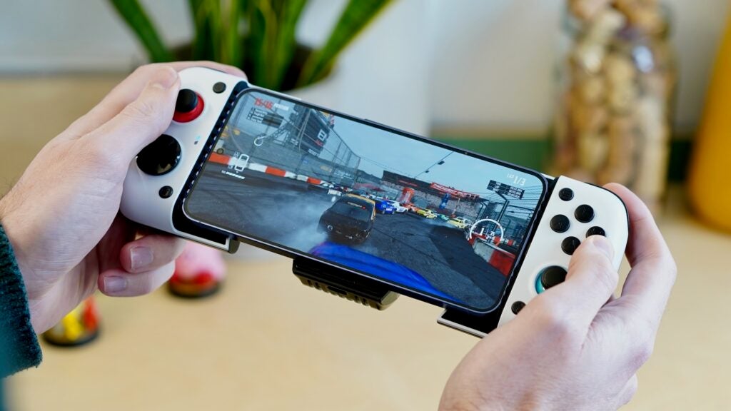 Mains tenant le contrôleur GameSir X3 attaché au smartphone avec jeu de course.